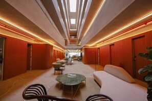 A modern hotel lobby with a central seating area, a staircase, and a view of the lobby in the background. - Setai Yacht - Garden III - By Almare (João Pessoa)