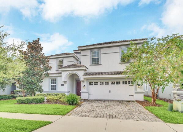 A two-story house with a garage, a driveway, and a well-maintained lawn.