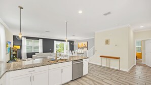 A modern kitchen with white cabinets, a granite countertop, and stainless steel appliances. - Spacious 9 Bed Pool Home with Game Room-9036HS (Davenport)