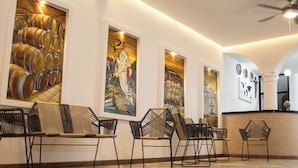 Un vestíbulo con mostrador de recepción, zona de estar con sillas y una obra de arte en la pared que muestra barriles y una persona con sombrero.