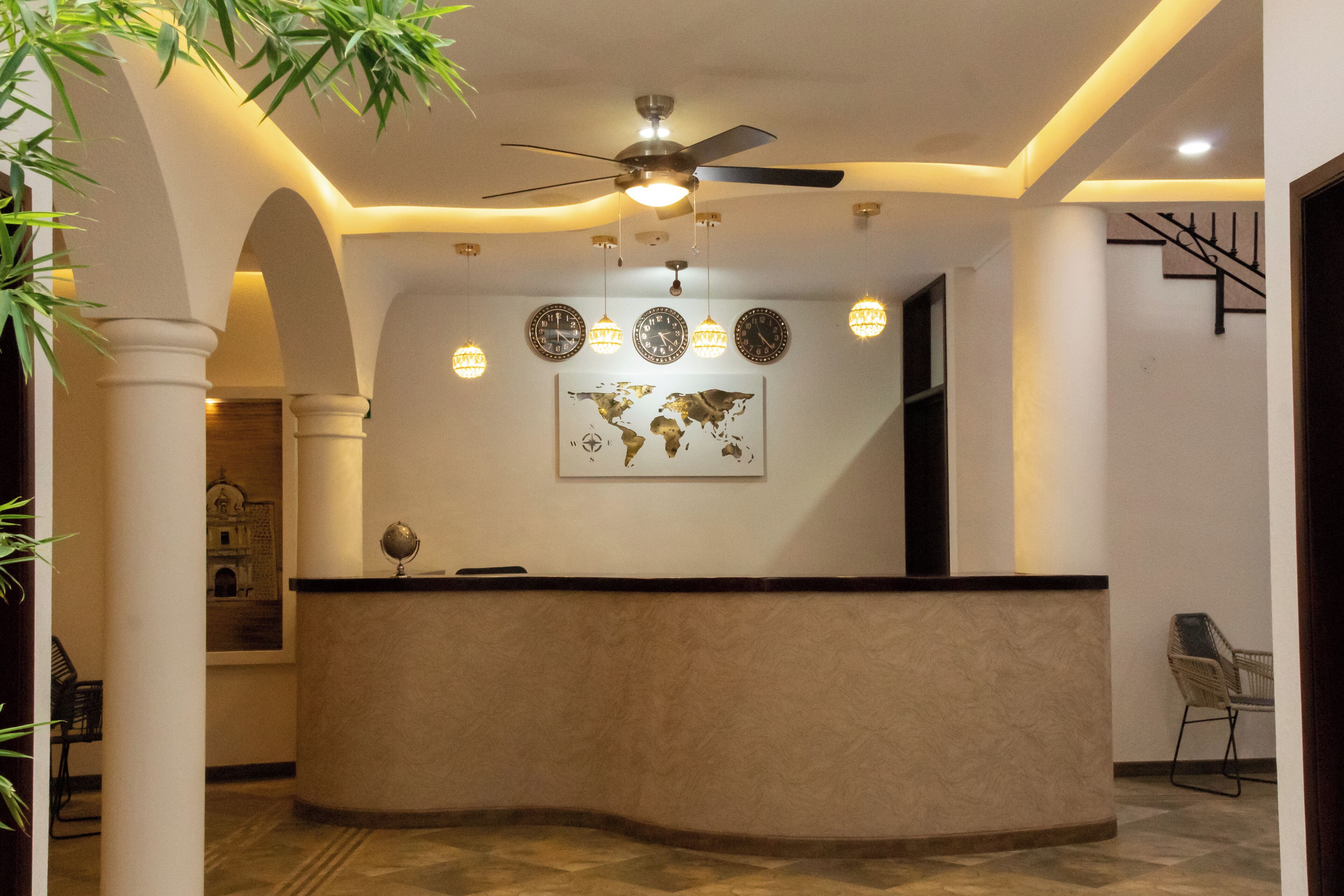 A reception area with a curved counter, a ceiling fan, wall clocks, and a world map.