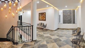 Un vestíbulo amplio con escalera, iluminación moderna y un área de descanso.
