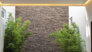 Un interior moderno con ventilador de techo, pared de piedra y plantas en macetas.