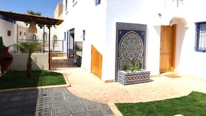 Un patio con entrada de baldosas, una palmera y una escalera que lleva a un edificio.