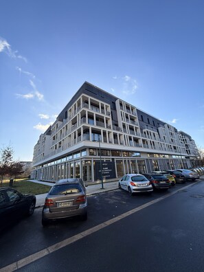 A modern multi-story building with a parking lot in front. - Brand NEW penthouse with rooftop Terrace next to Disneyland Paris (Montévrain)