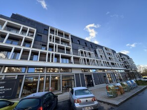 A multi-story building with balconies, large windows, and a storefront.