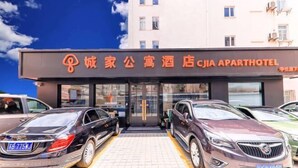 A hotel entrance with a sign in a foreign language, two cars parked in front, and a clear sky. - CJIA Apartment Hotel (Shanghai Zhongtan Road Subway Station) (Shanghai)