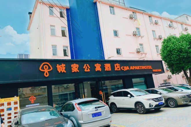 A hotel entrance with a signboard, multiple parked cars, and a building facade.