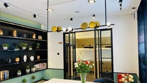 A modern interior with a white table, black shelves with decorative items, and a vase with flowers. - CJIA Apartment Hotel (Shanghai Zhongtan Road Subway Station) (Shanghai)