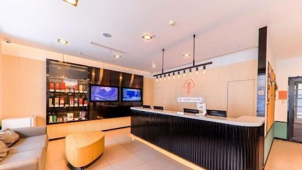 A modern hotel reception area with a black reception desk, two televisions, a seating area with a sofa and a round ottoman, and a wall-mounted sign reading "CBA APARTHOTEL". - CJIA Apartment Hotel (Shanghai Zhongtan Road Subway Station) (Shanghai)