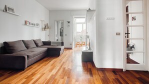 A modern living room with a sectional sofa, wooden flooring, and a white wall with shelves. - Deltico; 4 guests in washington area (Milano)