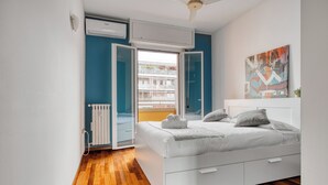 A bedroom with a white bed, a view of a building through an open door, and a ceiling fan. - Deltico; 4 guests in washington area (Milano)