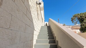 Eine Treppe führt zu einem Gebäude, im Hintergrund ein klarer, blauer Himmel.
