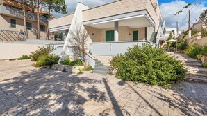 Un bâtiment moderne doté d’un toit plat, d’un porche couvert et d’un escalier menant à l’entrée.