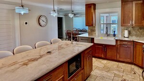 A kitchen with wooden cabinets, a marble countertop, a built-in oven, and pendant lighting.