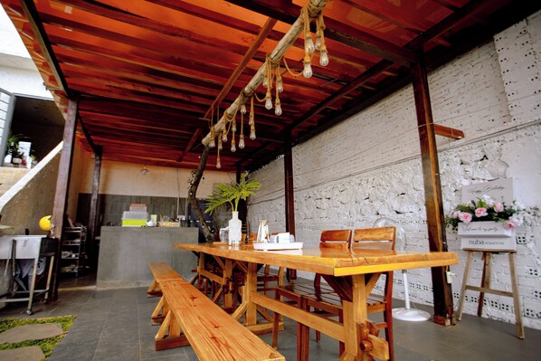A wooden dining area with benches and a table, a concrete counter, and a white brick wall.