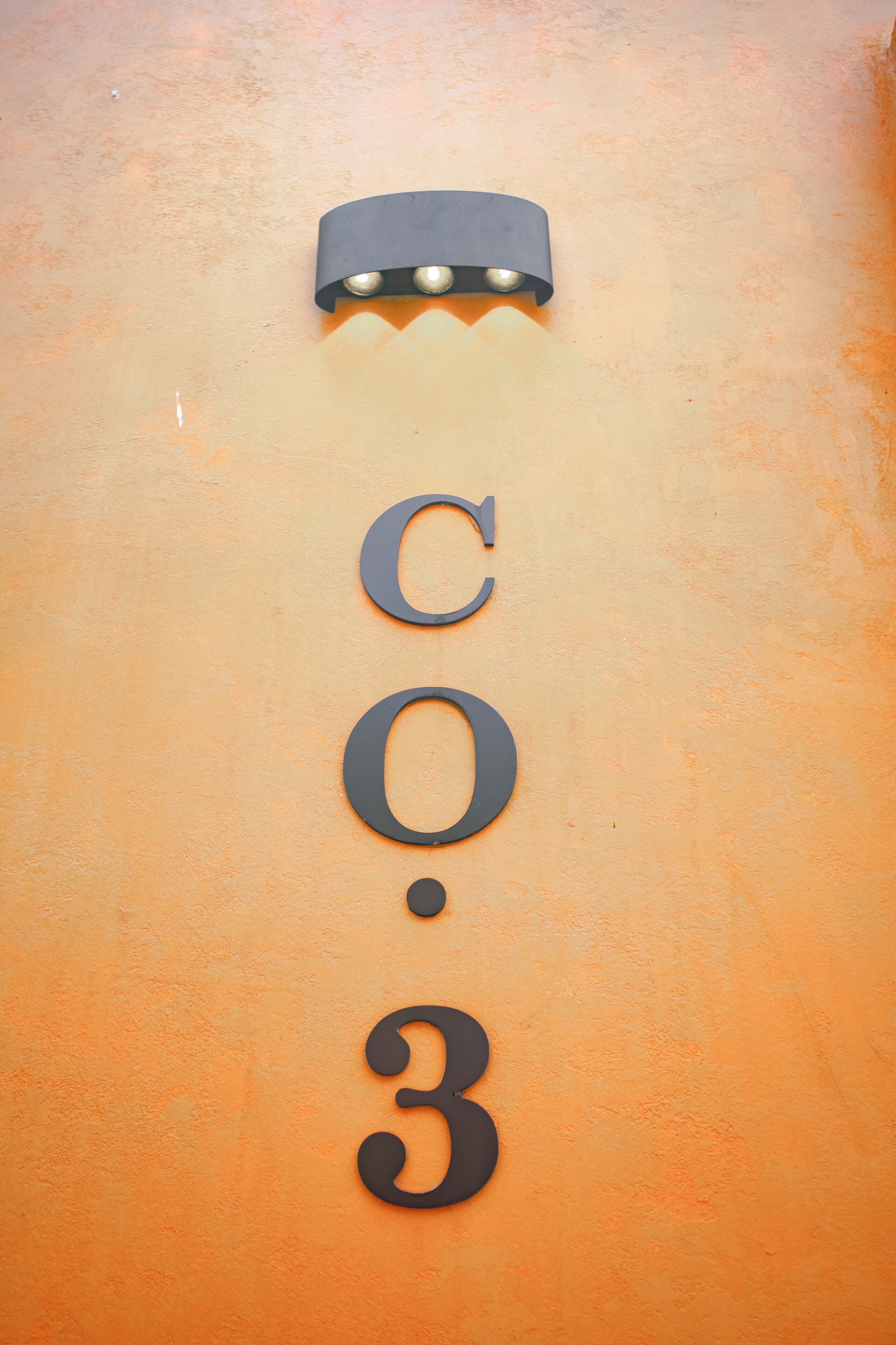 A wall with the numbers 'C.O.3' and a light fixture above it.