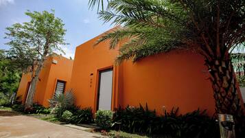 A building with a bright orange facade, a door, and surrounding greenery.