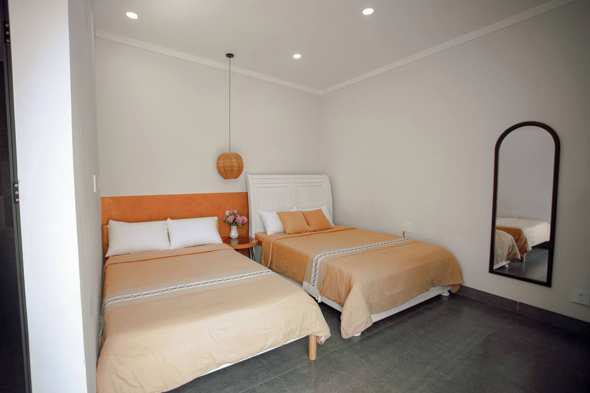 Une chambre d’hôtel avec deux lits, un miroir et un luminaire suspendu.