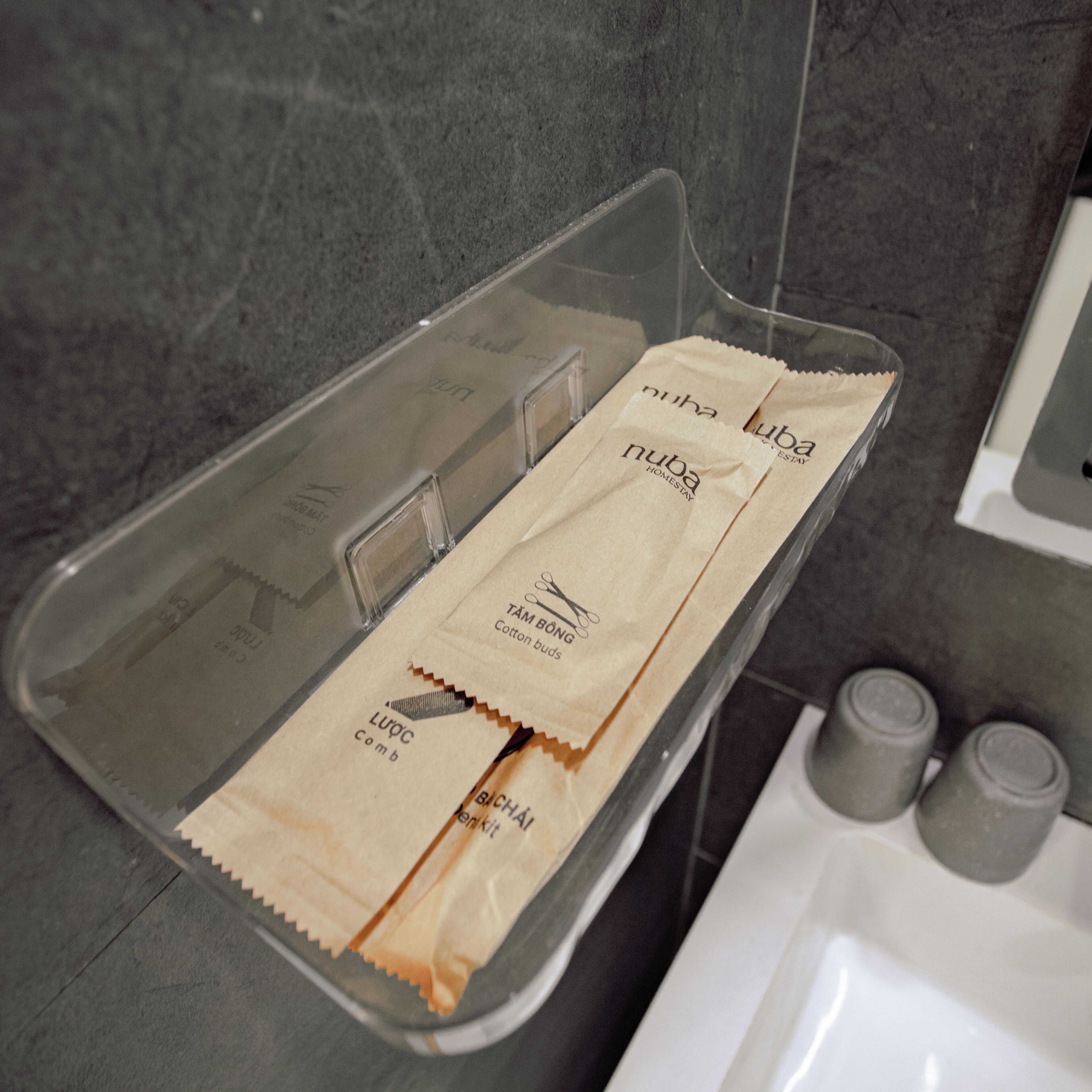 A bathroom with a clear shower tray, a white sink, and two bottles on the counter.