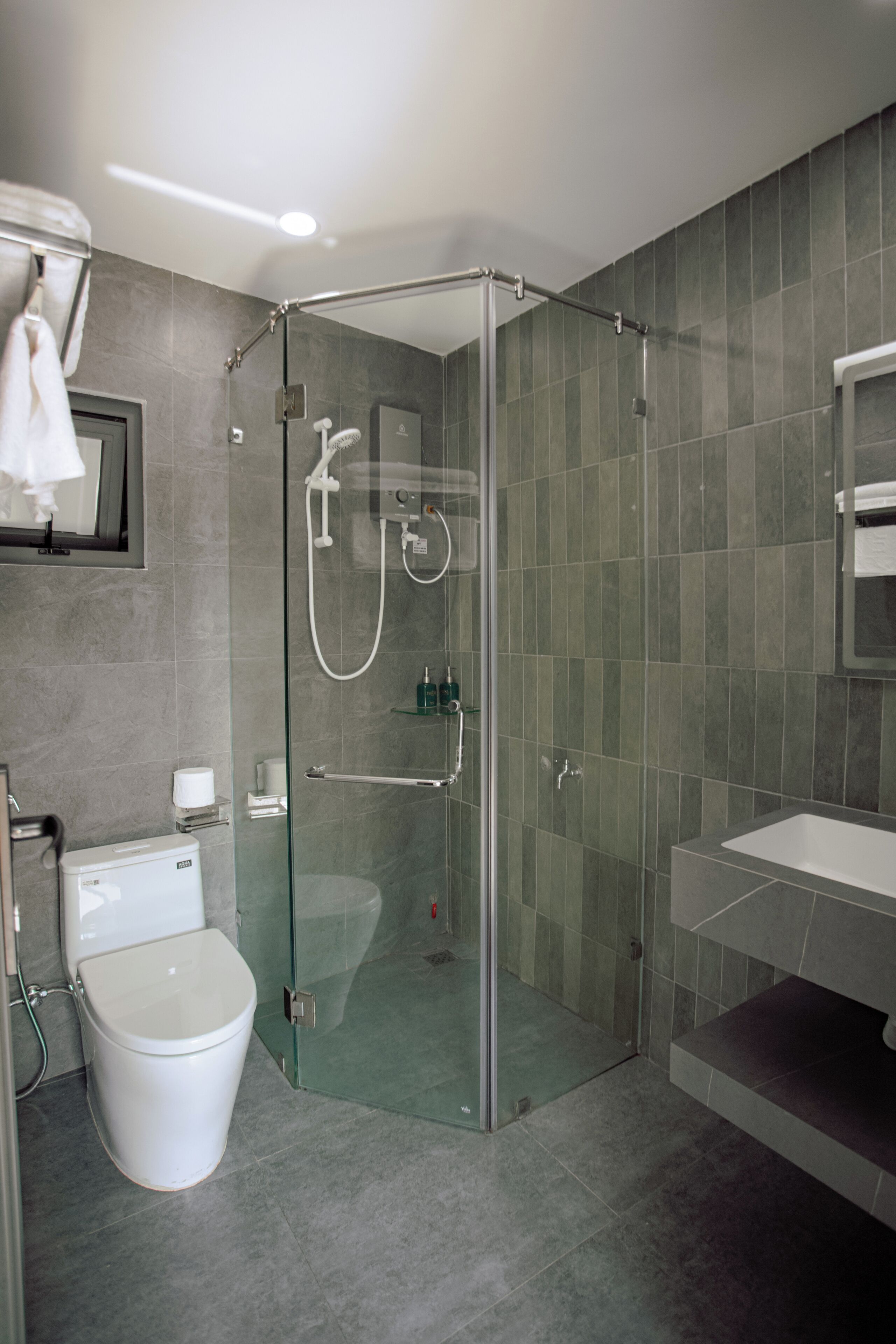 Een moderne badkamer met een douchecabine van glas, een toilet en een wastafel.