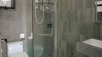 Een moderne badkamer met een douchecabine van glas, een toilet en een wastafel.