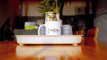 Un plato blanco con una taza blanca y dos vasos sobre una mesa de madera.