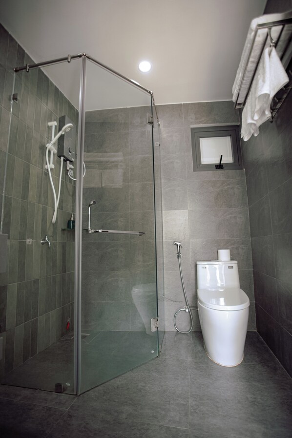 A modern bathroom with a glass-enclosed shower, a toilet, and a towel rack. - NUBA Homestay and Coffee Buon Ma Thuot (Buon Ma Thuot)