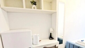 Una piccola cucina compatta con un frigorifero bianco, un lavandino bianco e una panca imbottita blu.