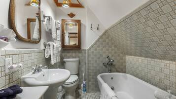A bathroom with a sink, toilet, and bathtub. There are towels hanging on the wall and a mirror above the sink.