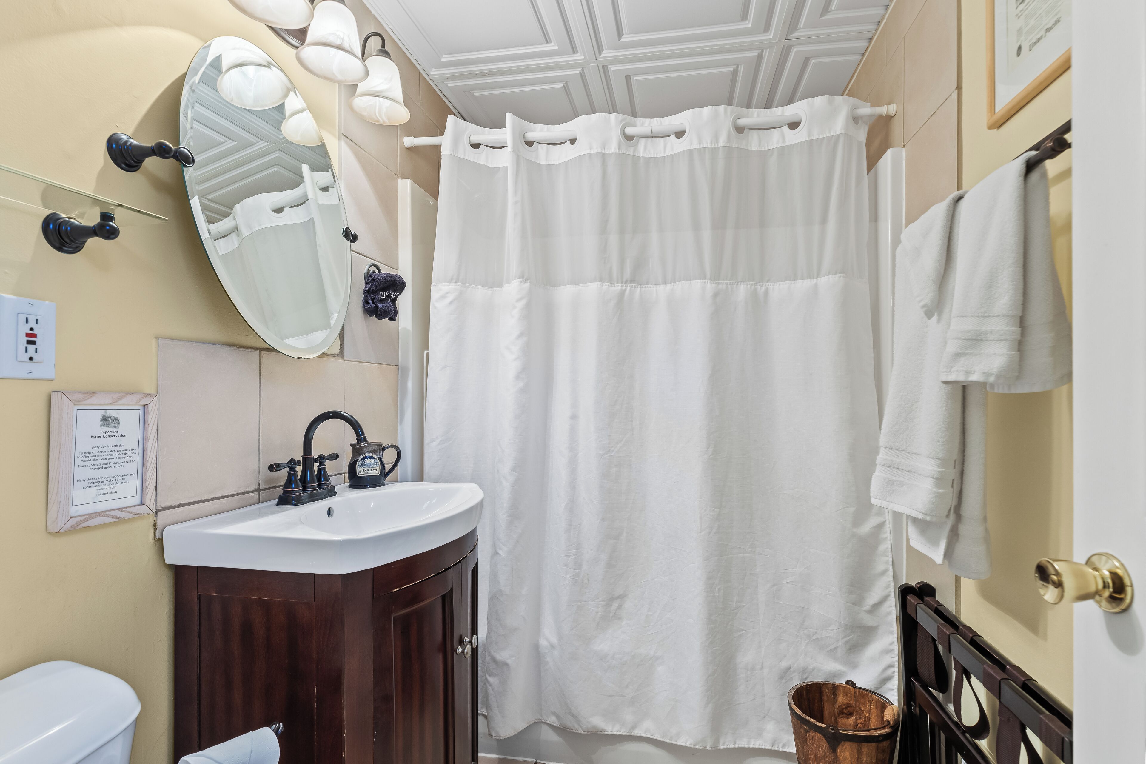 Une salle de bain avec un lavabo blanc, un meuble en bois foncé et un rideau de douche blanc.