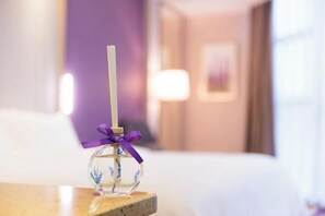 A clear glass bottle with a purple ribbon on a wooden surface in a hotel room. - Lavande Hotel(Dongguan Dongcheng Metro Station Wanda Plaza) (Dongguan)