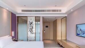 A modern hotel room with a large bed, a walk-in closet, a seating area, and a television on the wall. - Lavande Hotel(Dongguan Dongcheng Metro Station Wanda Plaza) (Dongguan)