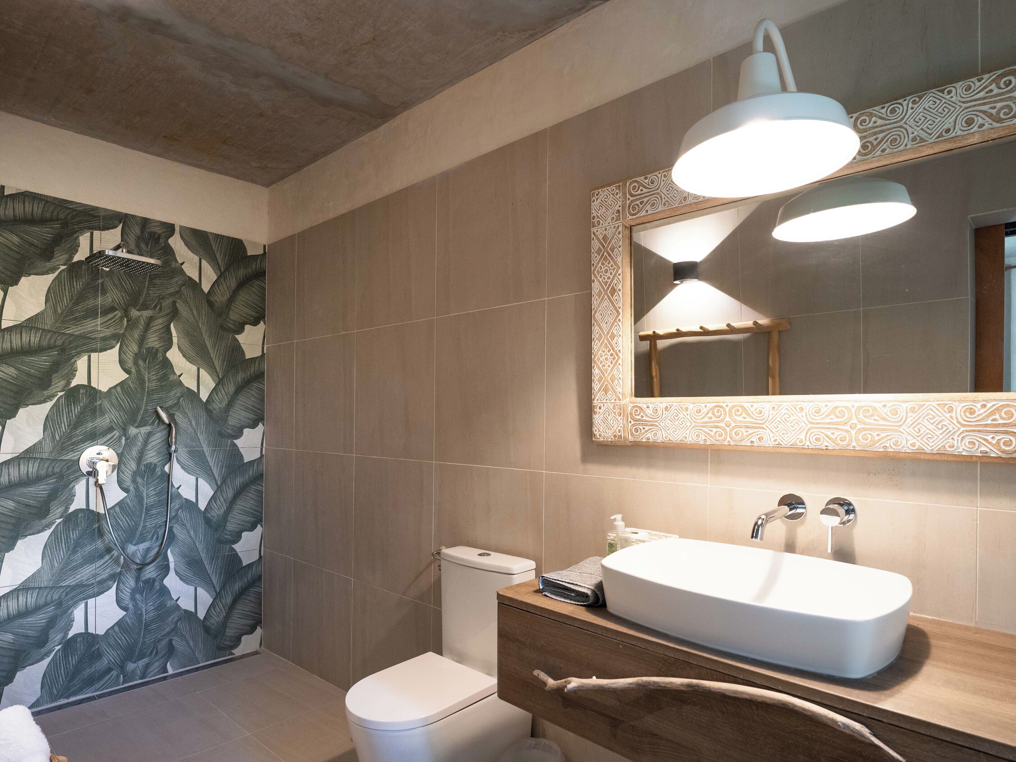 Un bany amb un mirall gran, un lavabo i un vàter.