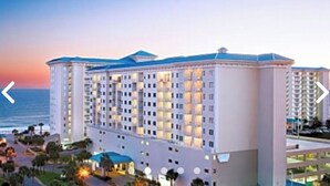 A multi-story hotel with a modern design, featuring a prominent entrance and a view of the ocean.