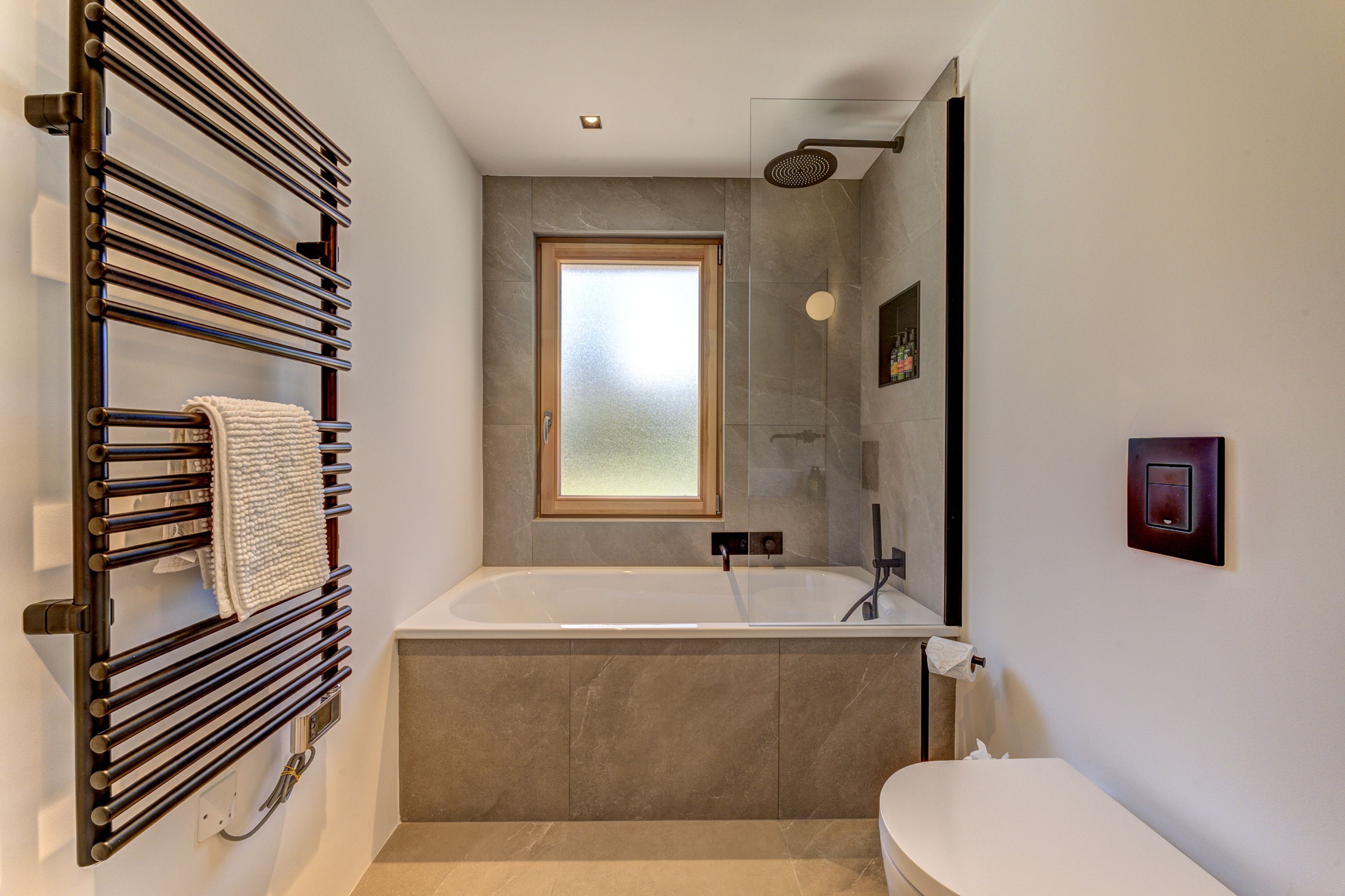Een moderne badkamer met een vrijstaand bad, een handdoekhouder en een grote spiegel.