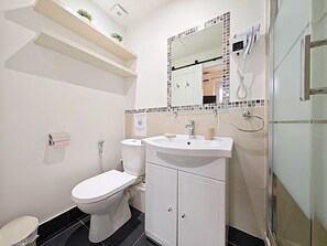 A bathroom with a toilet, sink, mirror, and shower. - Viva Riviera Croisette Carre d'Or (Cannes)