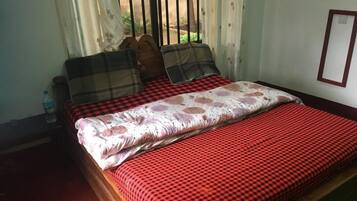 Un lit avec une couvre-lit à carreaux rouges et noirs, un coussin à motifs floraux et un coussin à carreaux.