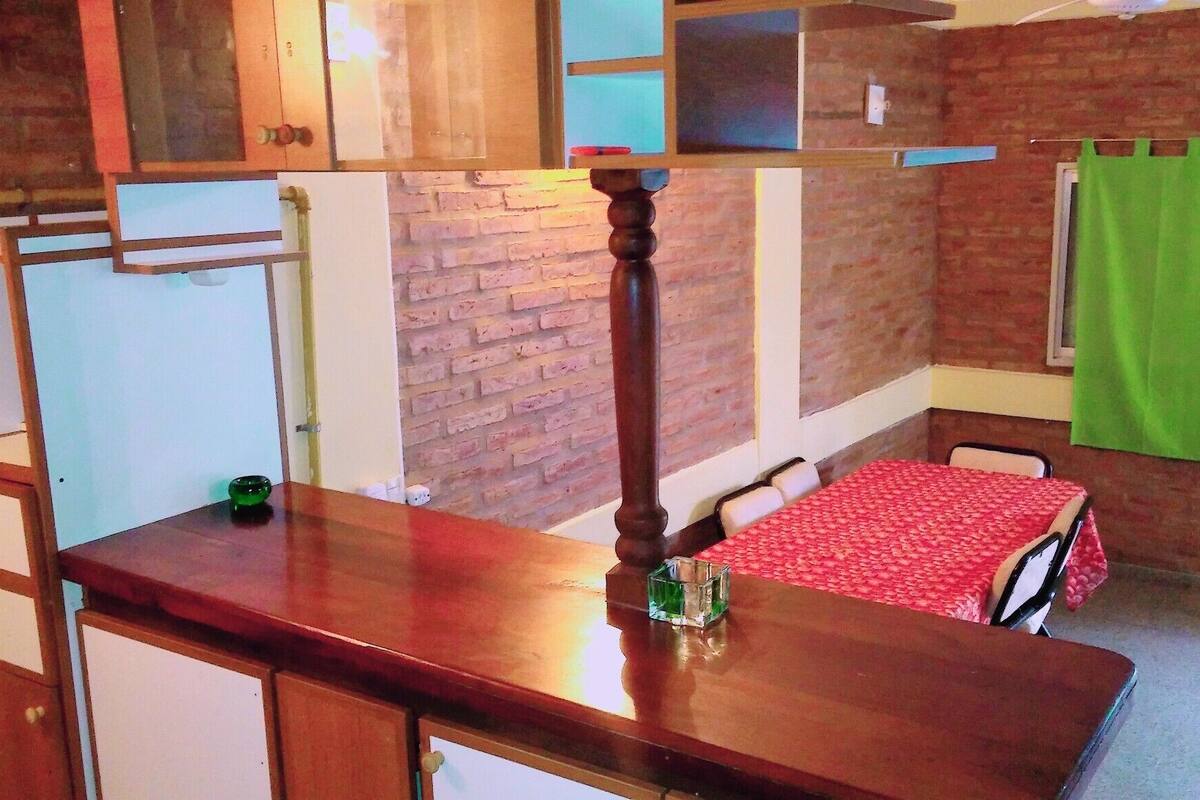 Una cocina compacta con armarios de madera, una encimera y una pared de ladrillo.