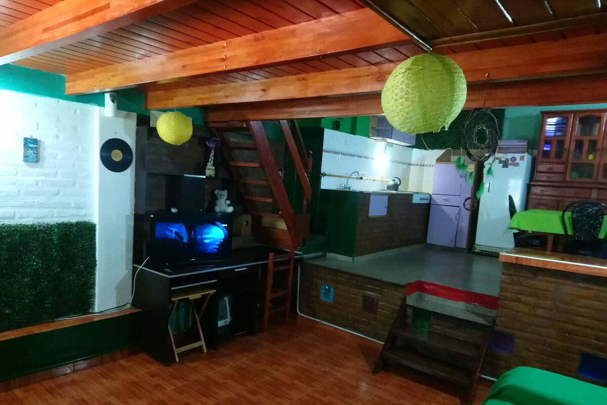 Una cocina compacta con techo de madera, un refrigerador pequeño y un lavamanos.