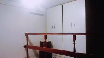 A room with a wooden railing, white cabinets, and a basket on the floor.
