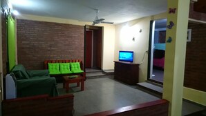 Een woonkamer met een bank, een televisie en een plafondventilator.
