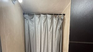 Un baño pequeño con inodoro, cortina de ducha y paredes de azulejos.