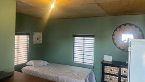 Una habitación con una cama, un escritorio, una lámpara fijada a la pared y un adorno mural.