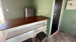 Una cocina pequeña con encimera de madera, un refrigerador y una puerta negra.