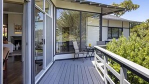 A modern house with a deck, large windows, and a covered outdoor seating area.