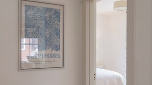 A room with a framed artwork on the wall, a door leading to another room, and wooden flooring. - Charming Downtown 2 BR Apartment Steps from Downtown Mall (Charlottesville)