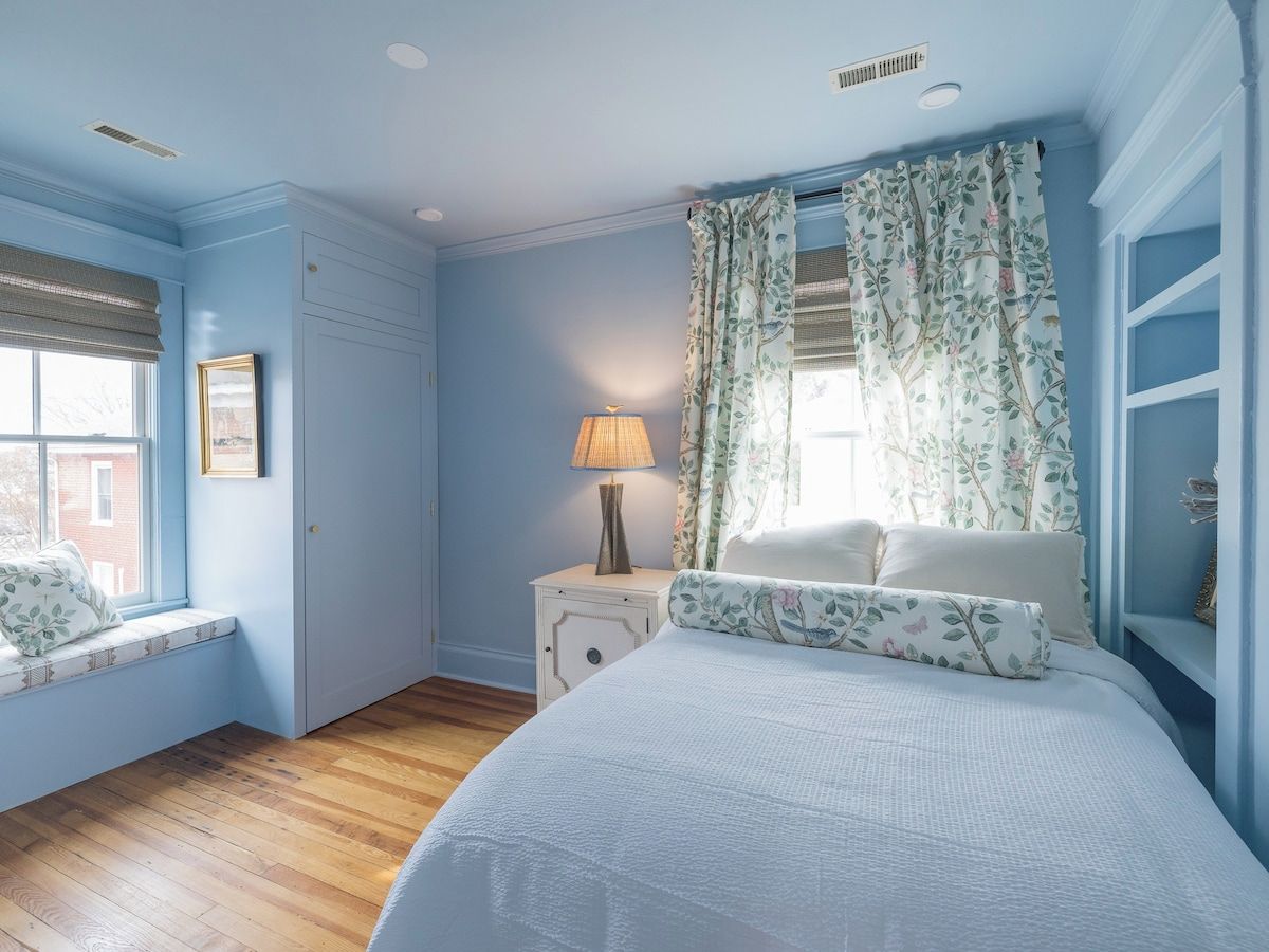 Een slaapkamer met een groot bed, een nachtkastje met lamp, een raam met uitzicht en een inbouwkast.