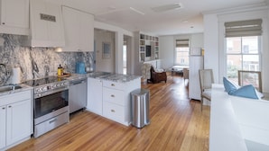 A spacious kitchen with white cabinetry, a marble backsplash, and a built-in oven. - Charming Downtown 2 BR Apartment Steps from Downtown Mall (Charlottesville)