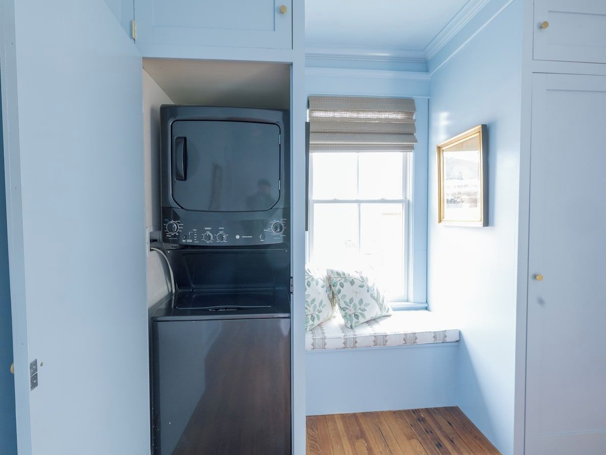 A compact kitchen with a built-in microwave and oven, a window with a view, and a small seating area with cushions.